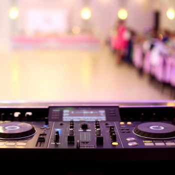 A DJ turntable with an empty dance floor in the background