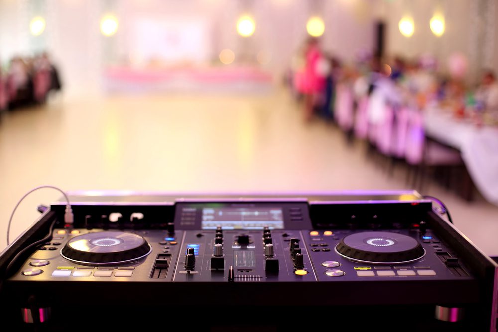 A DJ turntable with an empty dance floor in the background 