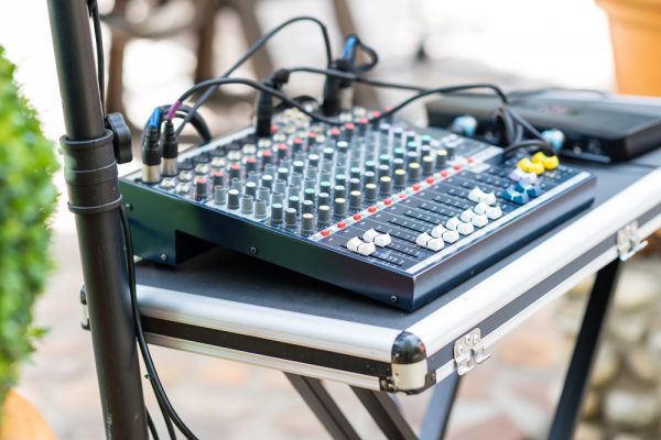 A mixer sits on a table as part of a DJ setup during an outdoor event