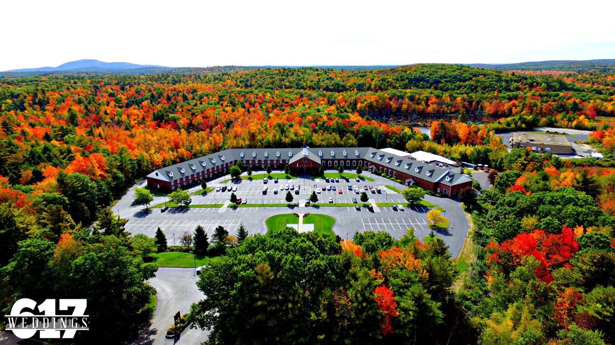 The u-shaped Colonial Hotel in MA surrounded by colorful fall foliage.