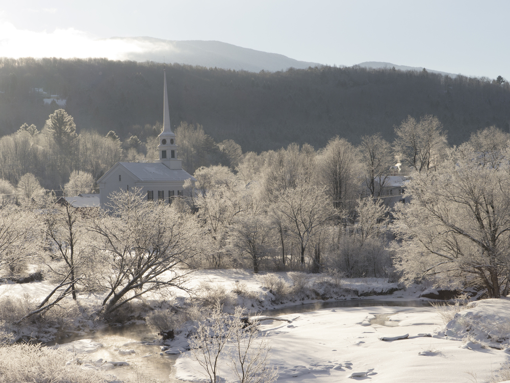 Frost covered trees and a white church steeple on a winter's morning in Stowe, VT.