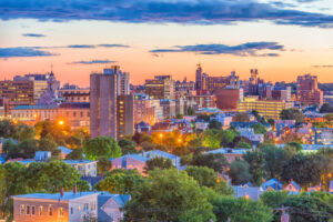 The skyline of Portland, ME surrounded by trees at dusk.