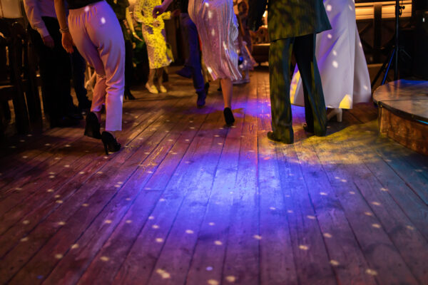 Dancing feet on a wooden floor, lit with party lights during a wedding reception