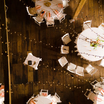 Aerial view of a barn wedding, with white tables and string lights.